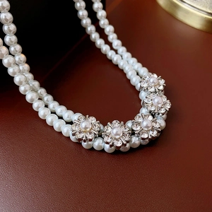 Macro shot of double-layer pearl necklace featuring silver rhinestone floral charms
