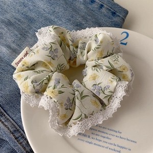 Macro detail of floral chiffon scrunchie with white lace trim and Sweet Girl tag