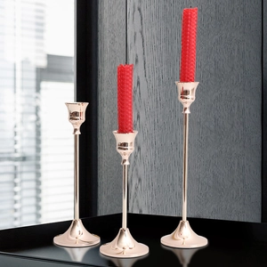 Three-piece rose gold metal candle holders with slim stems and weighted conical bases