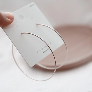 Minimalist large silver hoop earrings made of fine wire on a jewelry display card