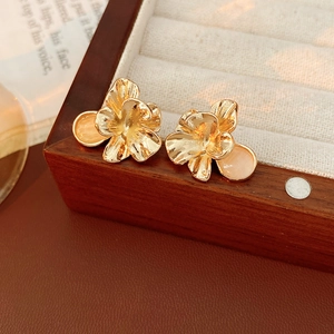 Close-up of golden vintage flower earring with cat-eye stone on a wooden jewelry box