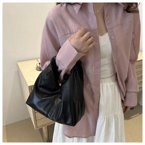 Model wearing a black ruched leather handbag in a vintage hobo style for casual daily use