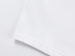 Macro detail of the double-needle stitching on the hem of a white off-shoulder cotton T-shirt