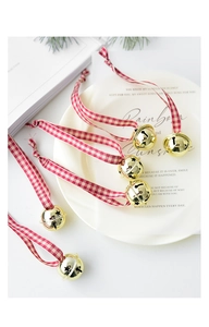 Detail of Christmas bell ornaments with cutout stars and red plaid ribbons on tray