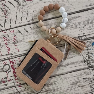 Detailed view of beaded wristlet with leather wallet, tassel, and zipper card slot