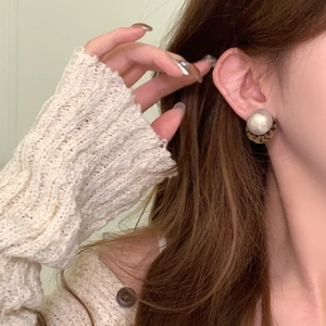 Close-up of leopard print round earrings with white pearl studs worn by a female model