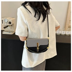 Detail of color-block crossbody bag featuring grey woven texture and gold vertical buckle
