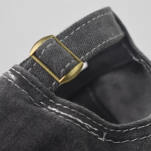 Macro detail of the adjustable brass metal buckle and vintage gray canvas strap on a baseball cap