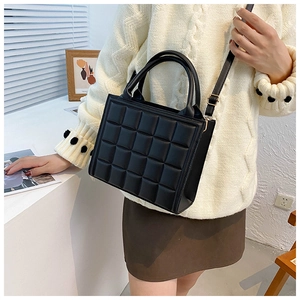 Detail of classic black checkered quilted crossbody bag styled with a minimalist outfit