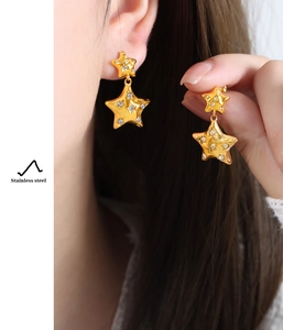 Detail view of gold stainless steel star drop earrings with sparkling zircon inlay
