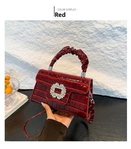 Détail du sac à main rouge effet croco avec boucle strass et poignée plissée