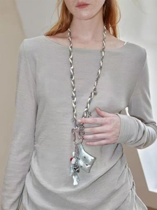 Close-up of a long hand-woven punk necklace with a soft pillow pendant and colorful beads