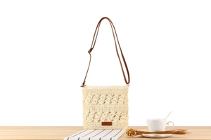 Detail of hollow woven summer beach bag in cream white with brown thin strap