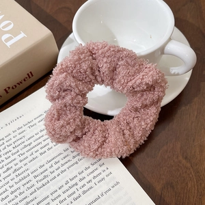 Detail of soft pink faux shearling scrunchie on a decorative white porcelain cup
