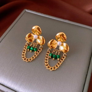Detail of gold flower earrings with white pearls and green striped bead tassels