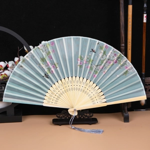 Detail of a light blue Chinese silk folding fan with bamboo ribs and flower pattern