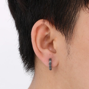 Macro shot of retro silver Cuban link stud earring with textured surface on male model
