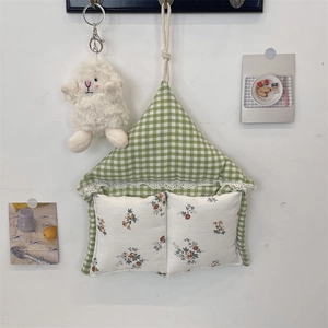Detail of fabric wall hanging organizer with green plaid, lace floral pockets and cute plush decor