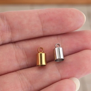 Handheld display of 18K gold and silver stainless steel cord end caps for DIY jewelry