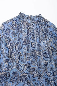 Dettaglio del collo alto a ruches e motivo paisley con filo glitter argento su top blu