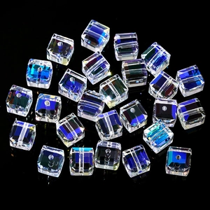 Macro detail of aurora AB cubic glass beads with center holes on black mirror surface