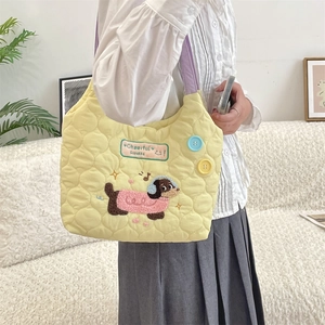 Detalle del bolso acolchado amarillo con bordado de perro y correas moradas