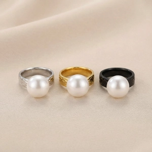 Detailed trio of pearl rings in gold, silver, and black finish on elegant fabric