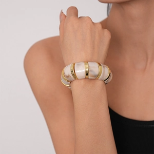 Detail of marble pattern acrylic stretch bracelet with gold metal accents on model wrist