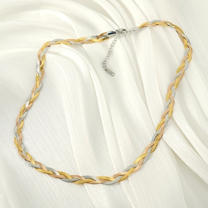 Detailed close-up of a three-tone braided snake chain necklace on white silk fabric