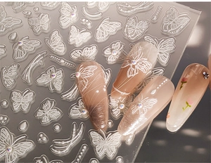 Gros plan d'autocollants 5D pour ongles avec papillons blancs et détails de texture en relief