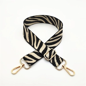 Close-up of zebra pattern woven bag strap with adjustable gold-tone metal buckles
