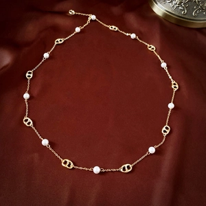 Detail of gold-plated pig nose link necklace with pearls on a red satin backdrop