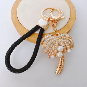 Golden coconut tree keychain with rhinestones, pearls and black braided leather strap