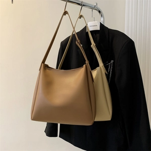 Detail of minimalist leather tote bags in caramel brown and cream white on a rack