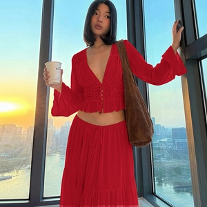 Detail view of red lace V-neck blouse and matching long skirt in a sunset city setting