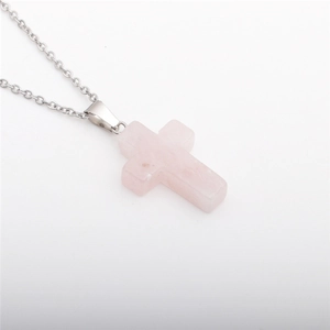 Detailed macro of rose quartz cross pendant on stainless steel chain necklace