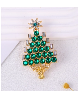 Close-up of gold Christmas tree brooch with green pearls and sparkling rhinestones