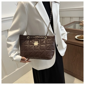 Dark brown quilted tote bag with chain strap and metal lock shown on a white blazer