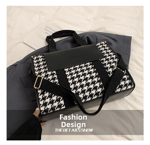 Detail showing the black and white houndstooth canvas texture and adjustable strap of tote bag