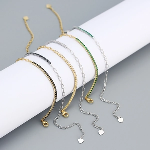 Detail of hybrid tennis and paperclip chain bracelets with zircon charms on a stand