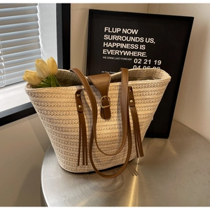 Detail of hand-woven beige straw tote bag with brown leather straps and metal buckle
