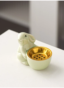 Detail of light green ceramic rabbit incense burner with a golden metal aroma bowl