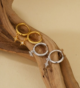 Detailed view of S925 silver star earrings with zircons hanging on a textured wood bark