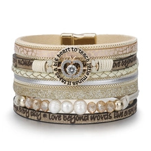 Detail of multi-layer leather bracelet with pearl accents and engraved charms