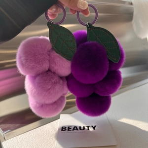 Gros plan de deux porte-clés raisins en peluche violette avec feuilles vertes