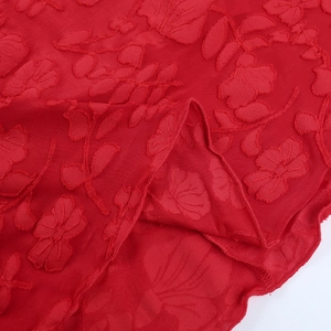 Dettaglio macro del tessuto jacquard floreale rosso con motivi in rilievo e bordi