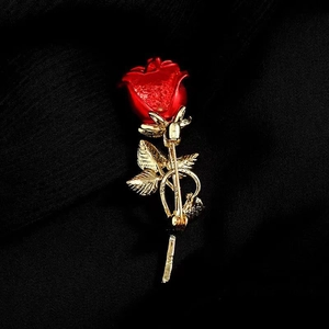 Macro shot of red rose brooch with golden leaves on black textured fabric background