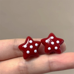 Détails de boucles d'oreilles étoiles rouges à pois blancs avec une finition en résine
