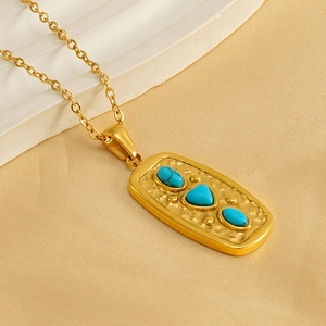 Detailed close-up of a vintage hammered gold pendant necklace with turquoise stones