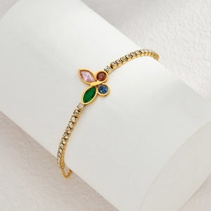 Gold butterfly bracelet with multi-colored zircon stones on a white display stand
